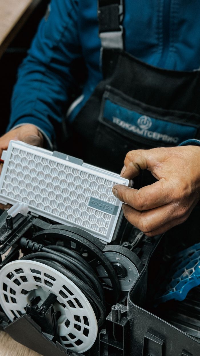 Close-up of a technician handling an air filter during a vacuum cleaner repair.
